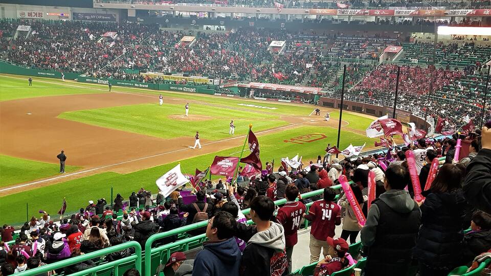 A baseball stadium filled with spectators, some holding flags.