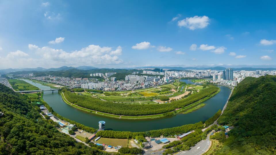Taehwa-dong, Jung-gu, Ulsan, South Korea - July 30, 2022: Aerial and panoramic view of Sibli Pine Forest and Taehwagang National Garden near Taehwa River aginst apartments in summer