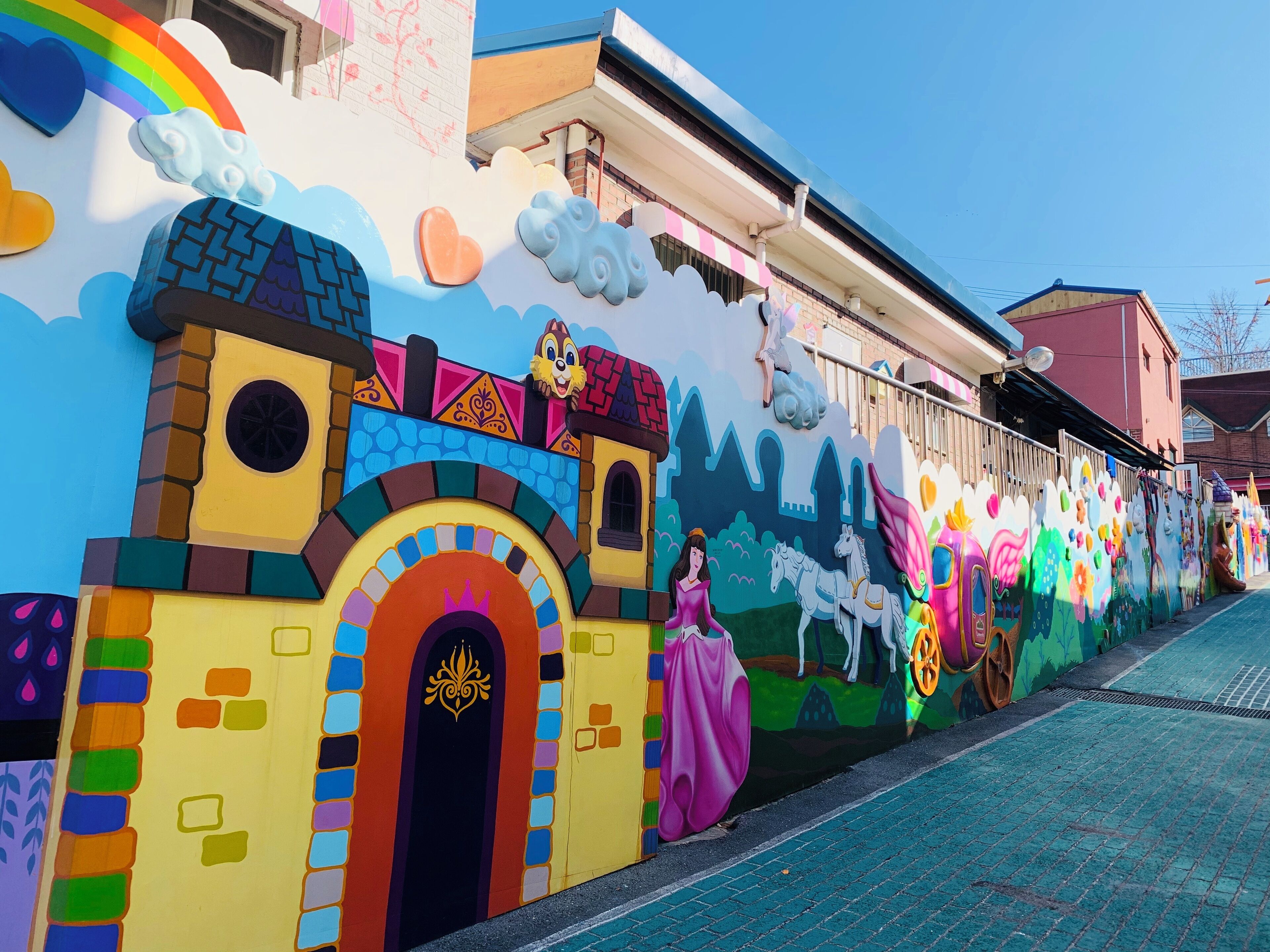 Um mural colorido com um castelo, um arco-íris e um personagem espiando.