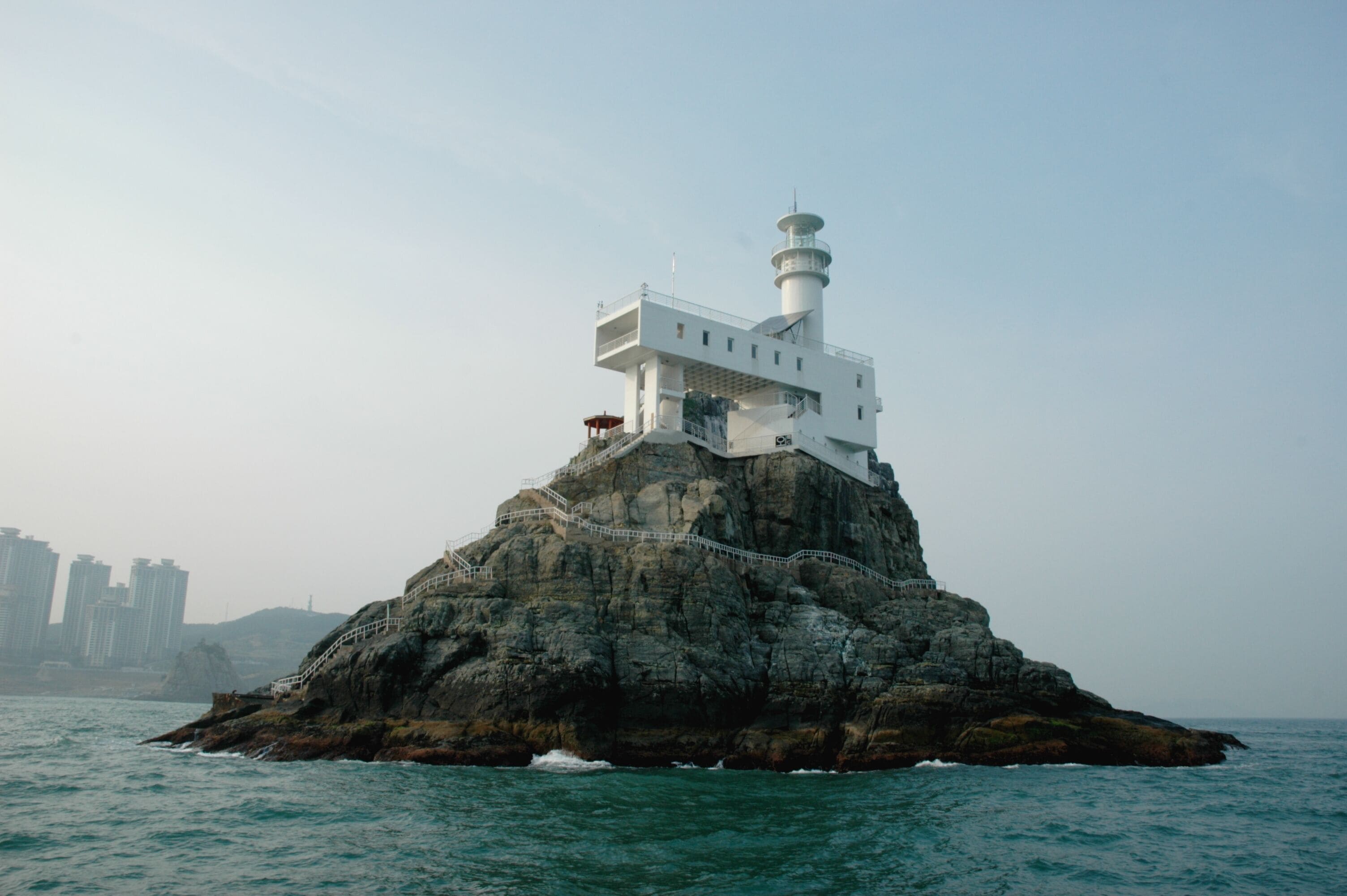 A lighthouse on a rocky island with a clear sky.