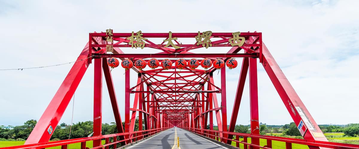 A red metal bridge with yellow centerline markings and Chinese characters on the side.