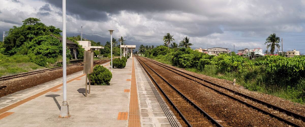A railway station with tracks, platform, and overhead electric lines.