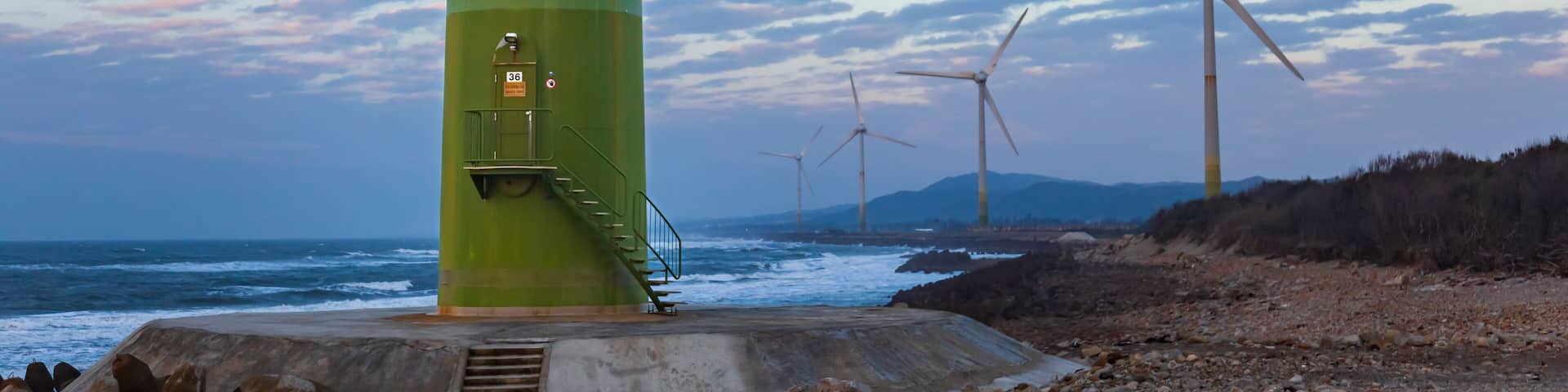 White wind turbines stand on the coast