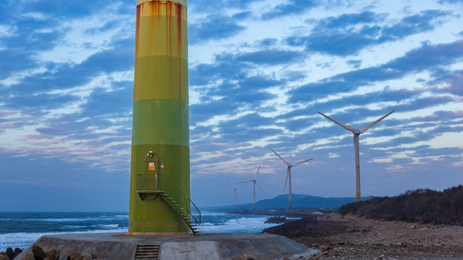 White wind turbines stand on the coast