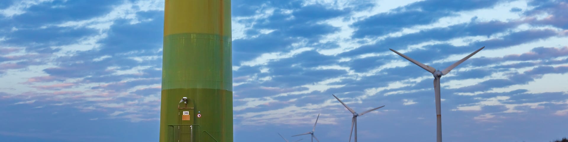 White wind turbines stand on the coast