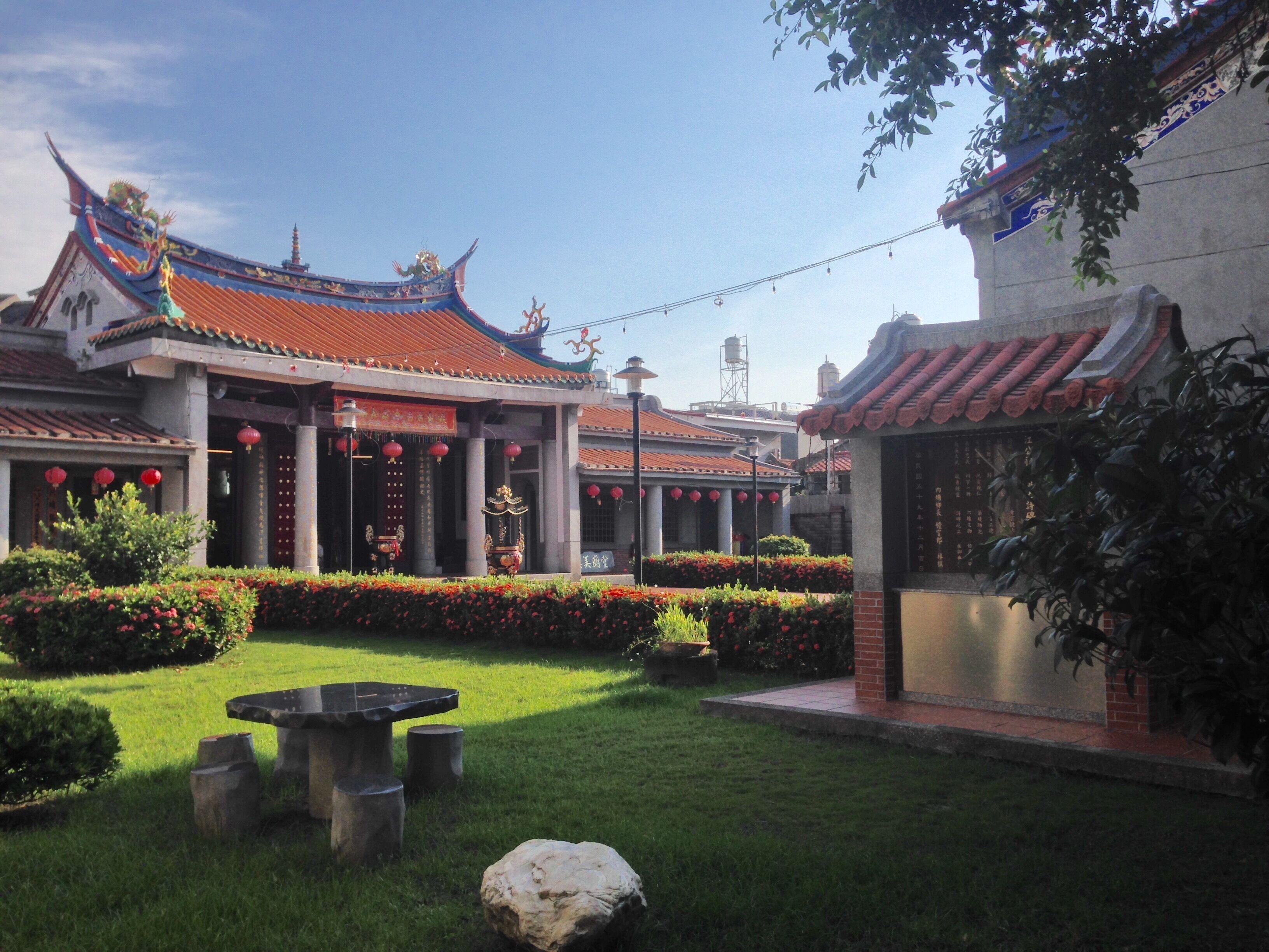 A traditional Chinese courtyard with ornate roofs, red lanterns, and well-maintained gardens.