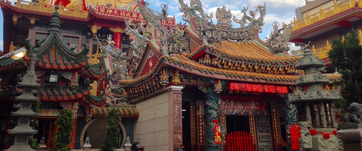 A traditional Chinese temple with ornate architecture, including a large golden statue, intricate roof designs, and red gates.