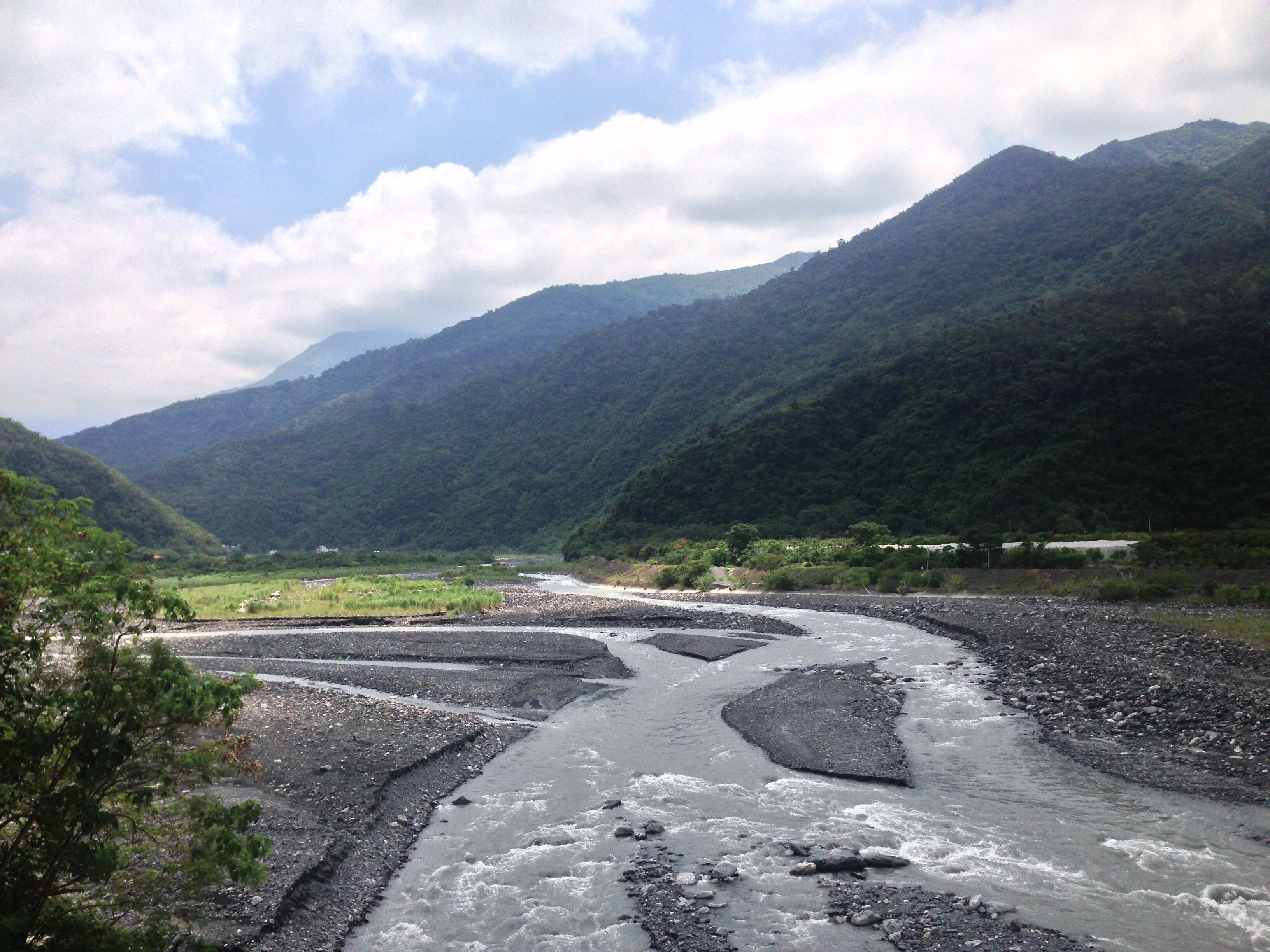 A river flowing through a valley with mountains in the background.