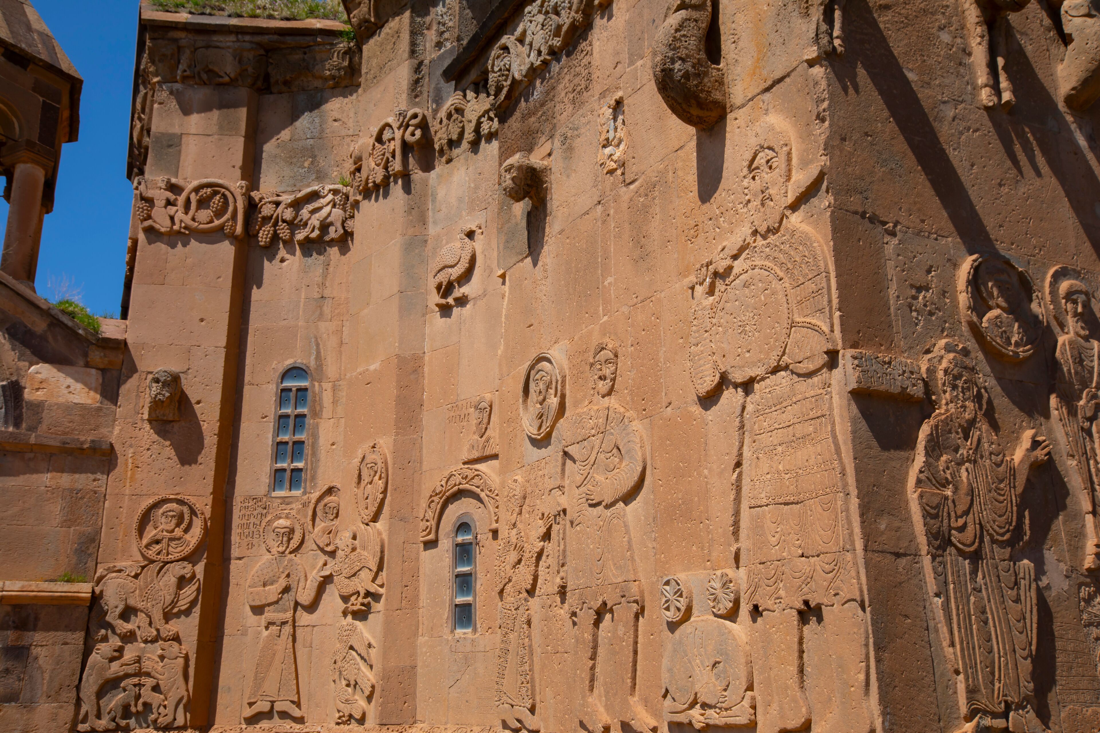 A detailed stone facade with religious carvings and a small window.