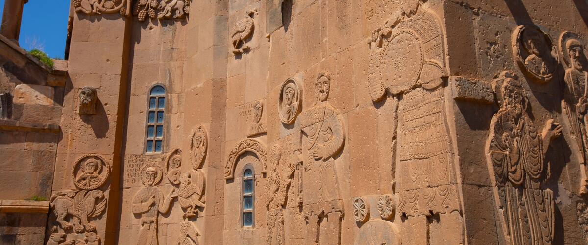 A detailed stone facade with religious carvings and a small window.