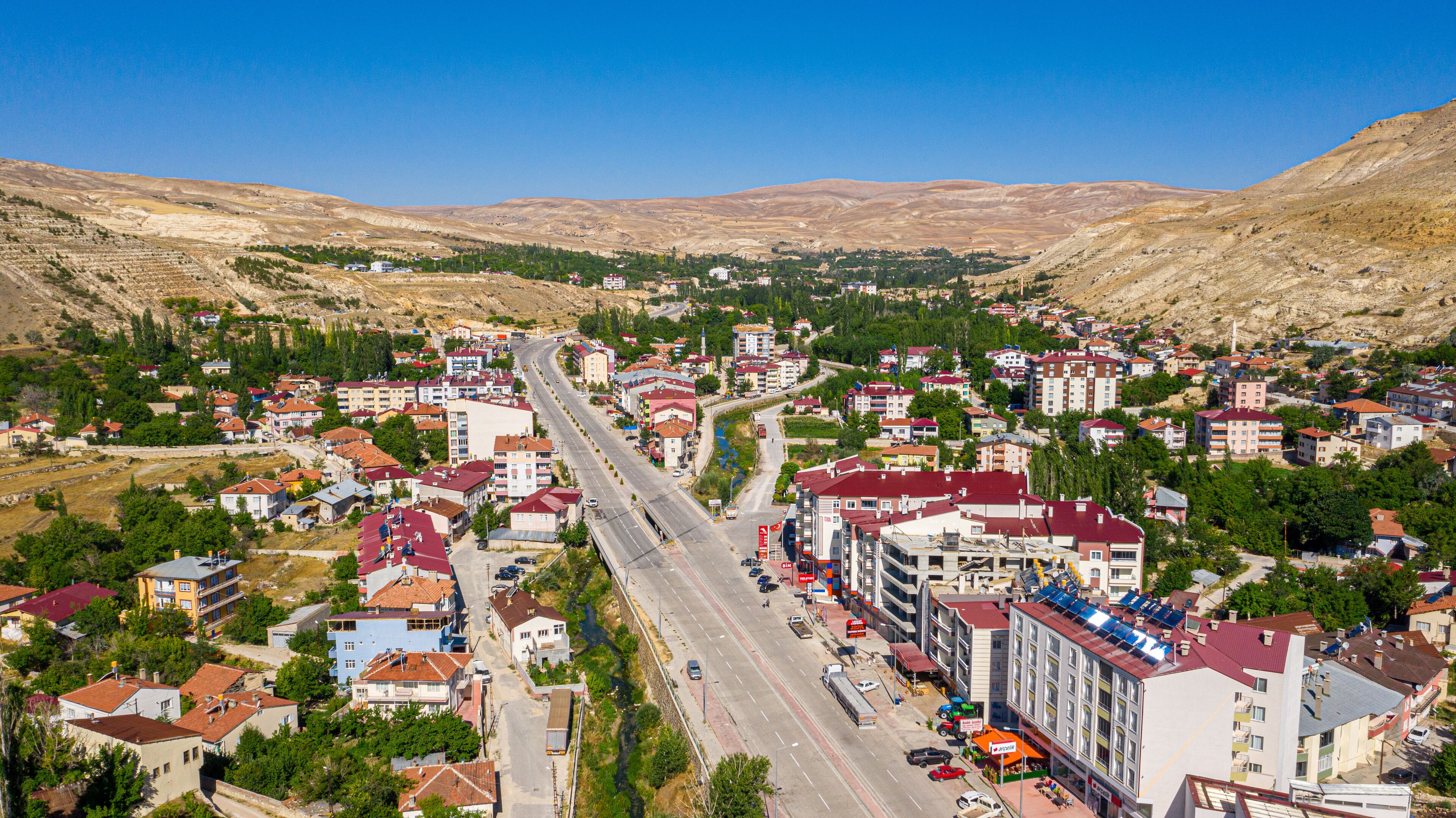 A town with a main road, buildings, and a mountainous backdrop.