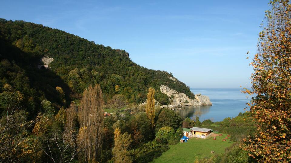 A coastal landscape with a rocky cliff, a small building, and a body of water.