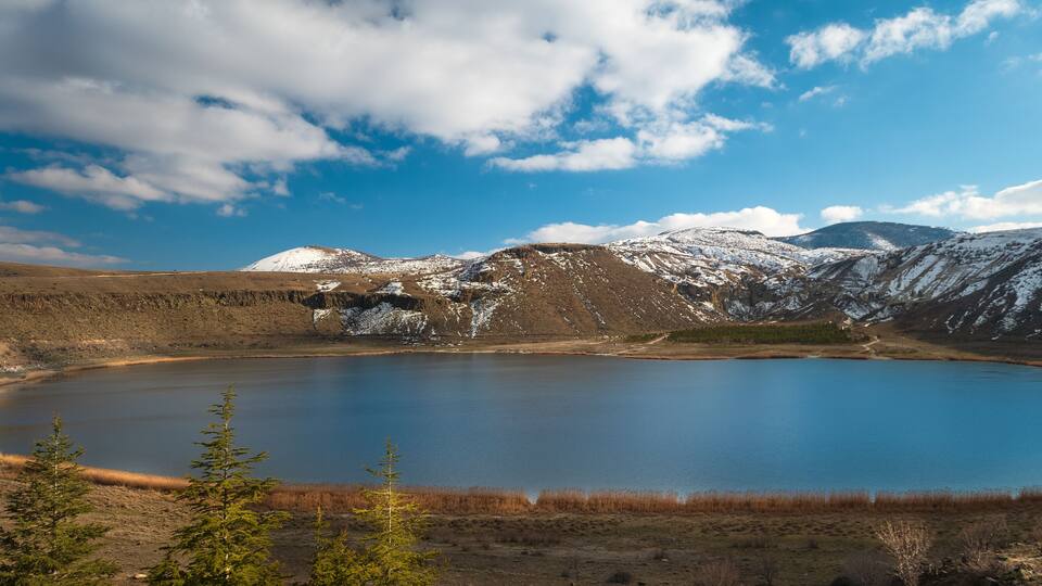 A lake surrounded by snow-capped mountains and a clear blue sky.