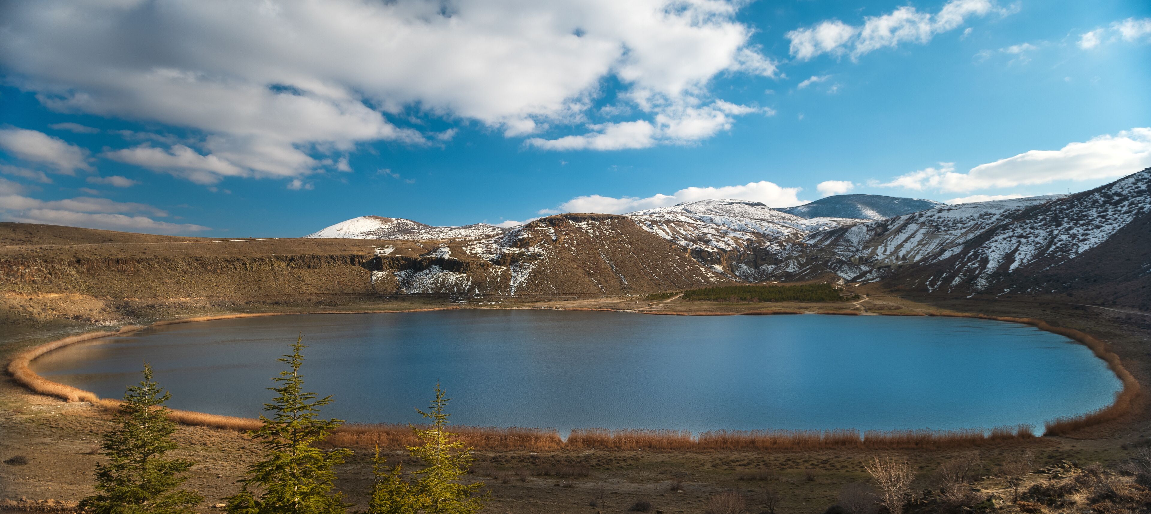 A lake surrounded by snow-capped mountains and a clear blue sky.