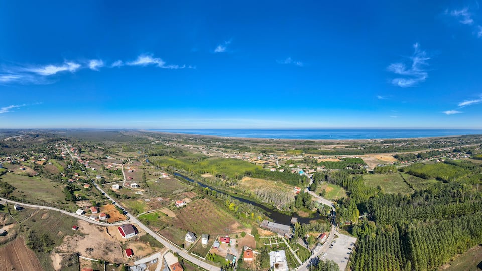 An aerial view of a rural landscape with fields, houses, and a river.