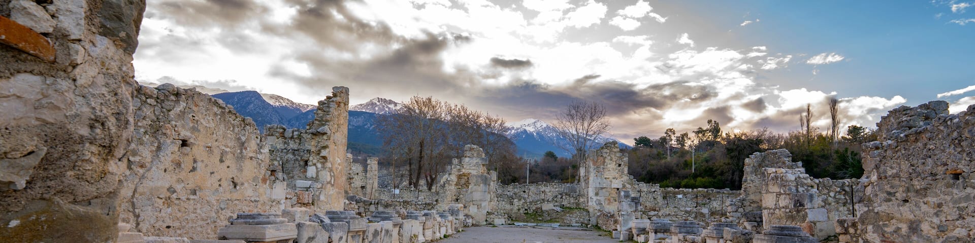 Ancient ruins with stone columns and a mountainous backdrop.