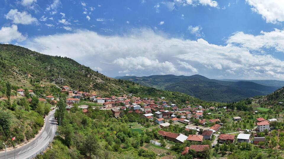 A panoramic aerial view of Kemaliye village in Keles, Bursa, Turkey. Surrounded by green hills and valleys, this peaceful rural landscape features traditional houses and a winding road Turkiye