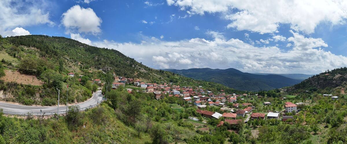 A village nestled in a valley surrounded by hills, with a winding road leading into the distance.