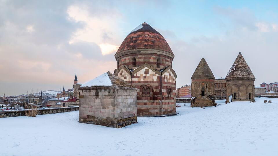 A snow-covered historical site with a prominent dome and two conical structures.
