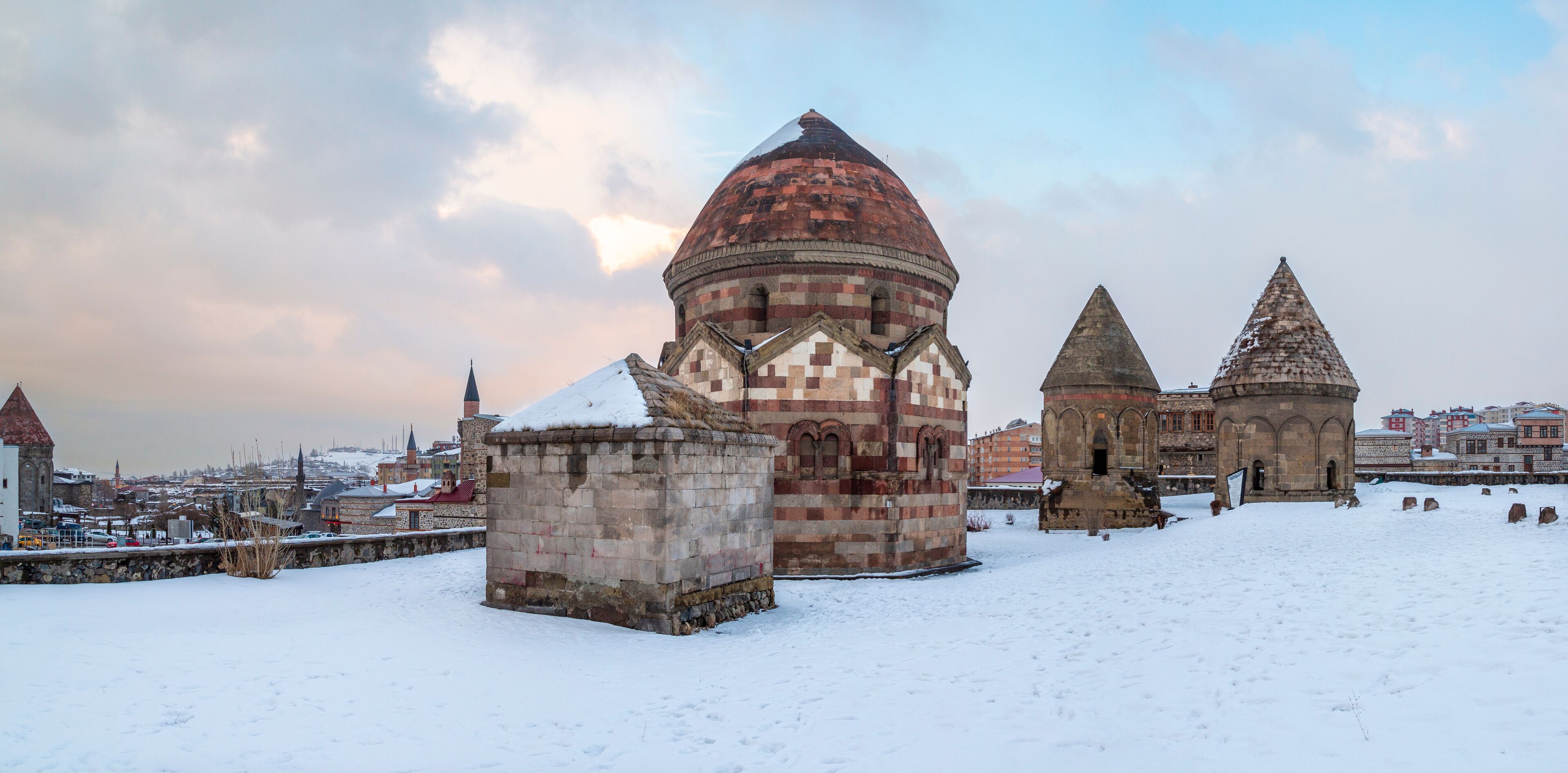 A snow-covered historical site with a prominent dome and two conical structures.