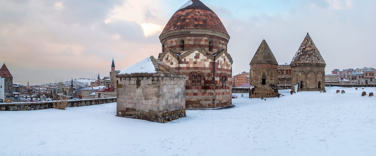 A snow-covered historical site with a prominent dome and two conical structures.