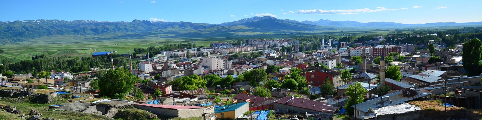 Un pueblo con una mezcla de edificios modernos y tradicionales, rodeado de campos verdes y montañas a lo lejos.