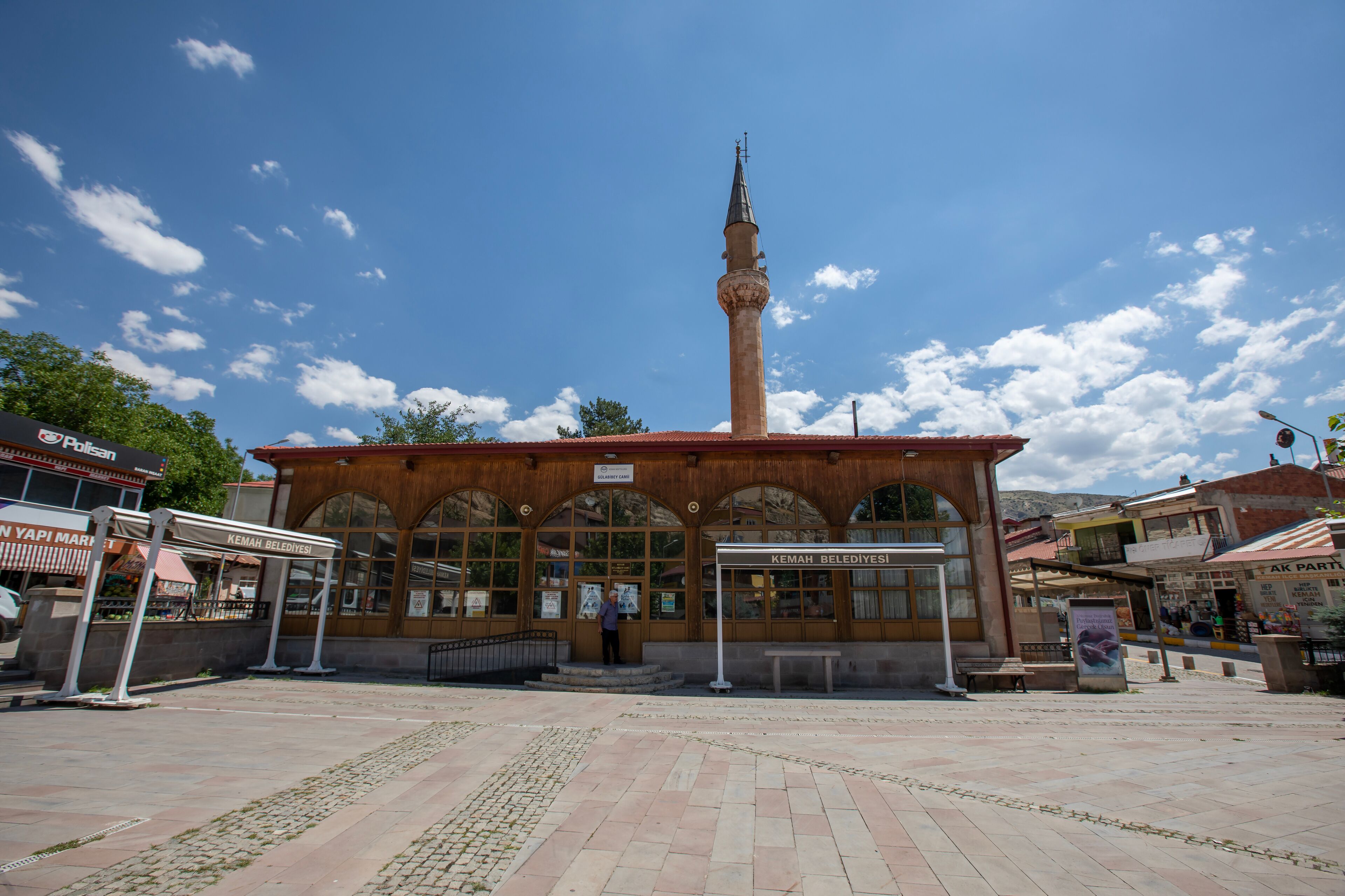 A mosque with a tall minaret, a covered entrance, and a tiled courtyard.