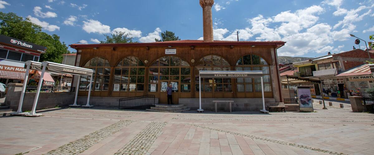 A mosque with a tall minaret, a covered entrance, and a tiled courtyard.