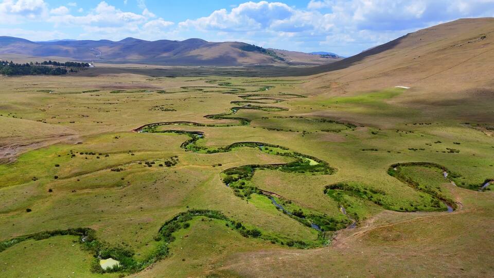 A vast landscape with winding streams and rolling hills.