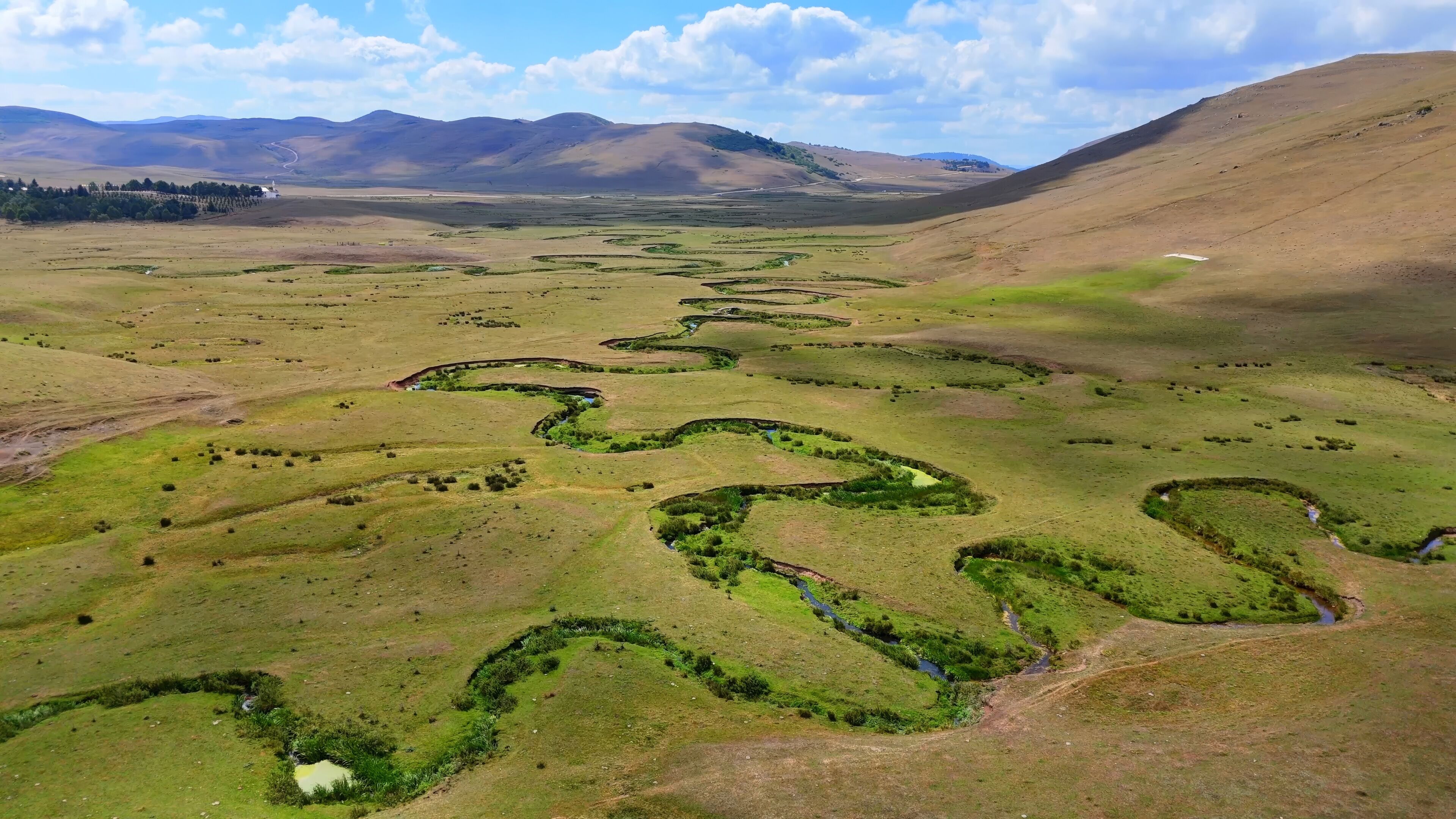 A vast landscape with winding streams and rolling hills.