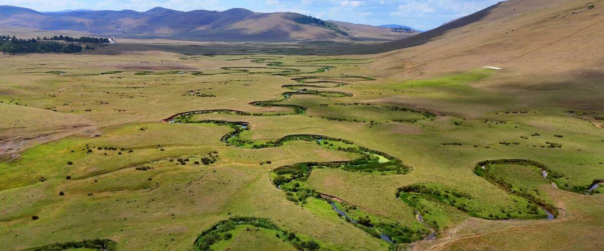 A vast landscape with winding streams and rolling hills.