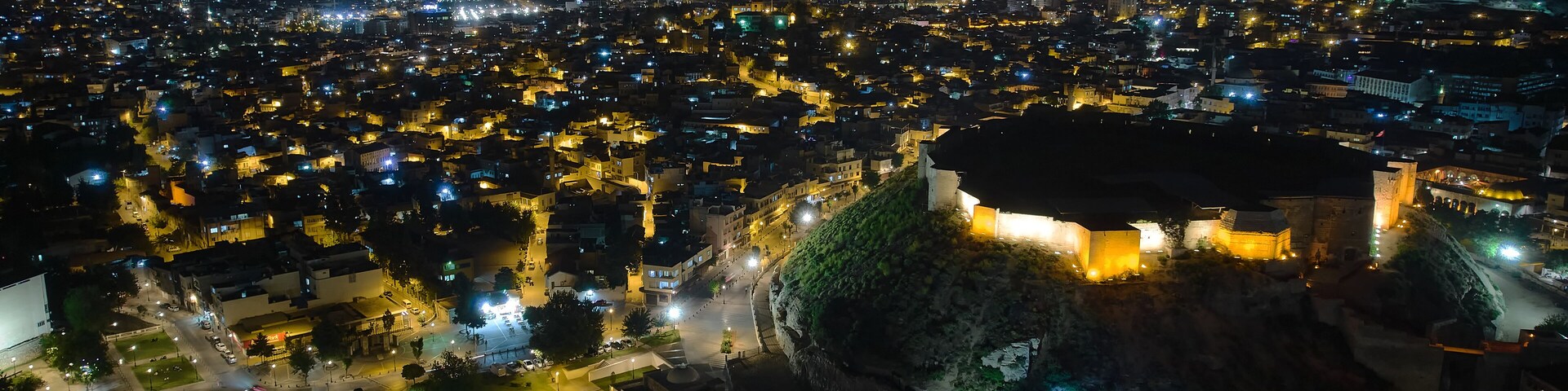 Illuminated Gaziantep Castle and night city lights aerial view. July 2022