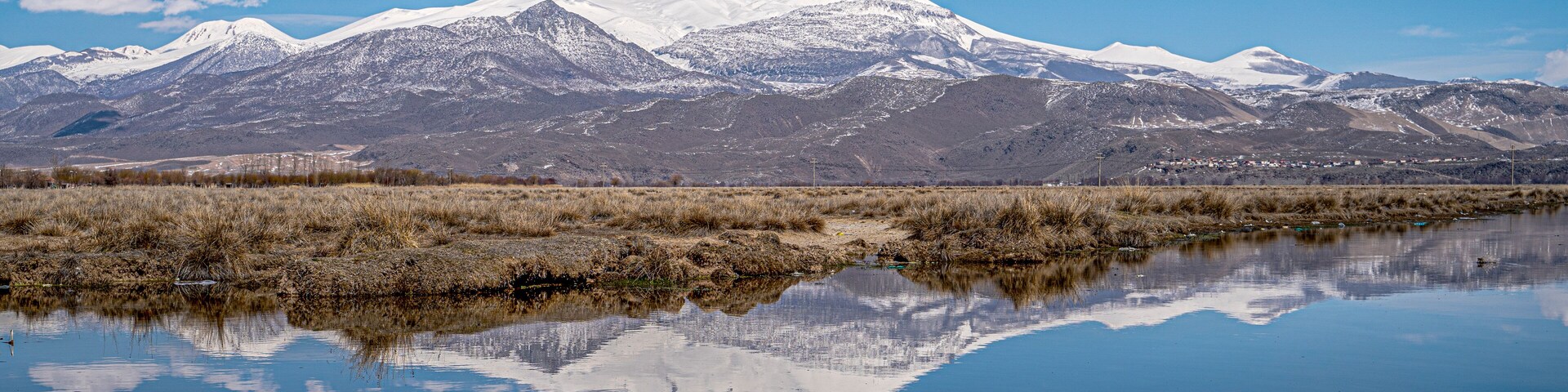 Una cordillera nevada reflejada en un lago tranquilo con cielo azul despejado.
