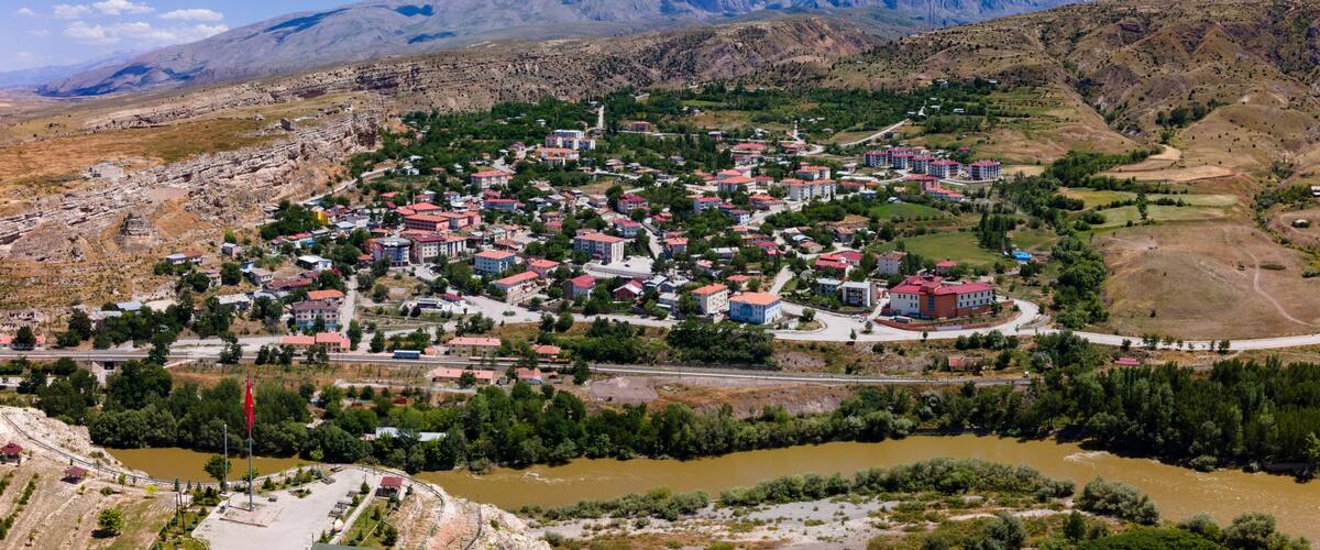 A town nestled in a valley with a river, surrounded by mountains.