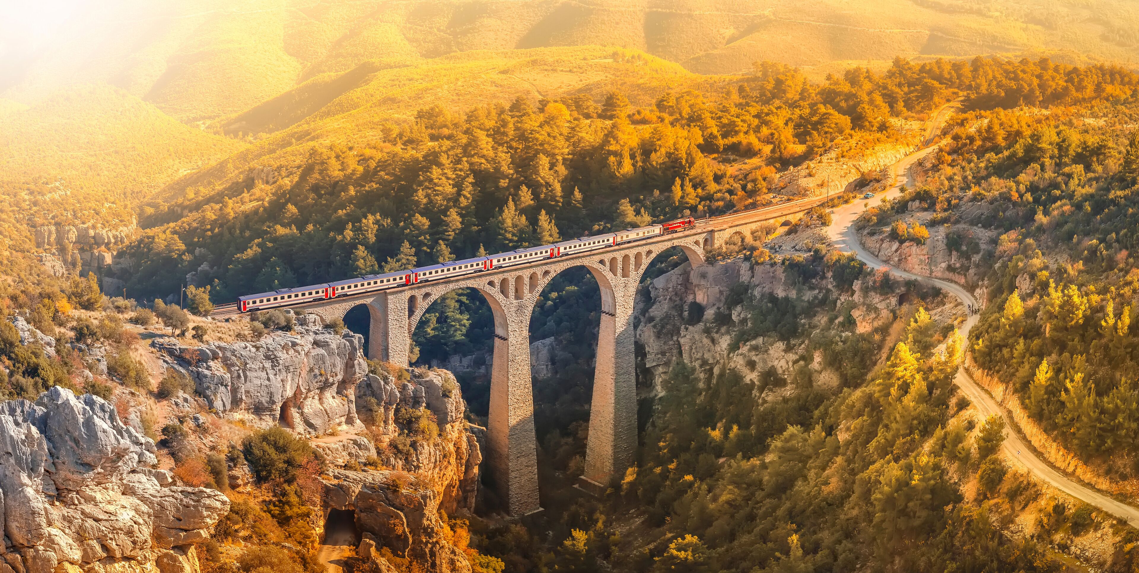 A train crossing a stone bridge over a canyon.