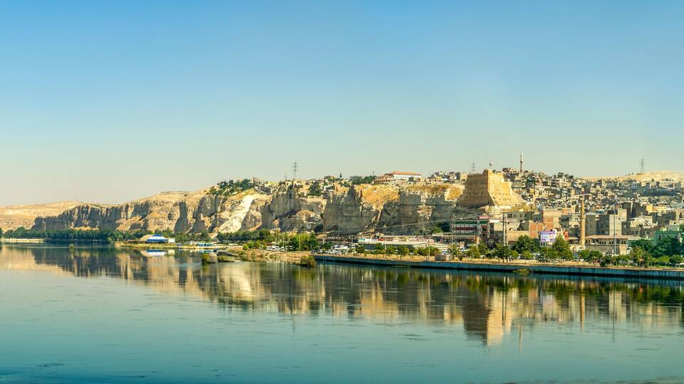 A cityscape with a river, a prominent fortress, and a mosque.