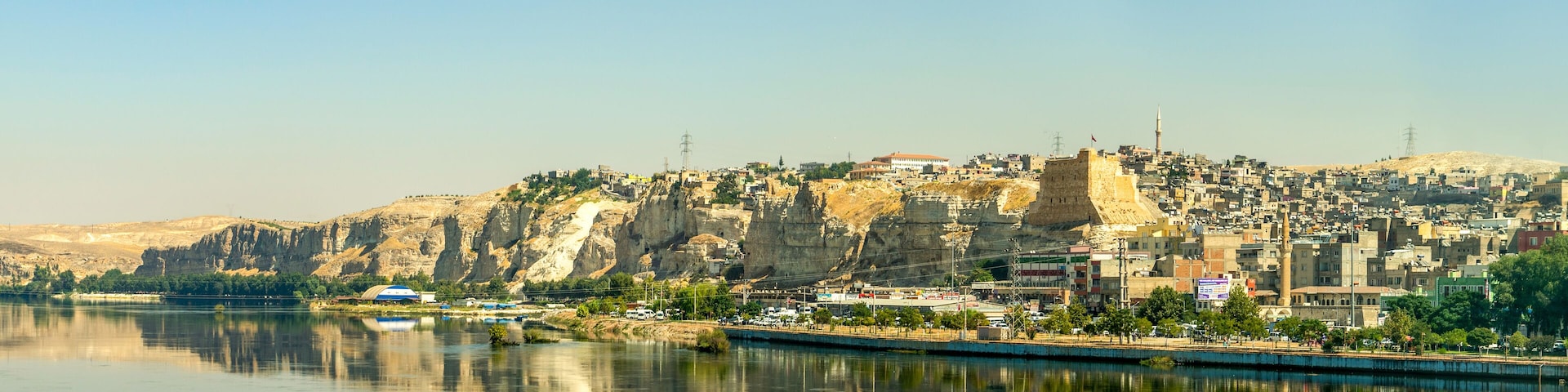 Paisagem urbana com rio, uma fortaleza imponente e uma mesquita.