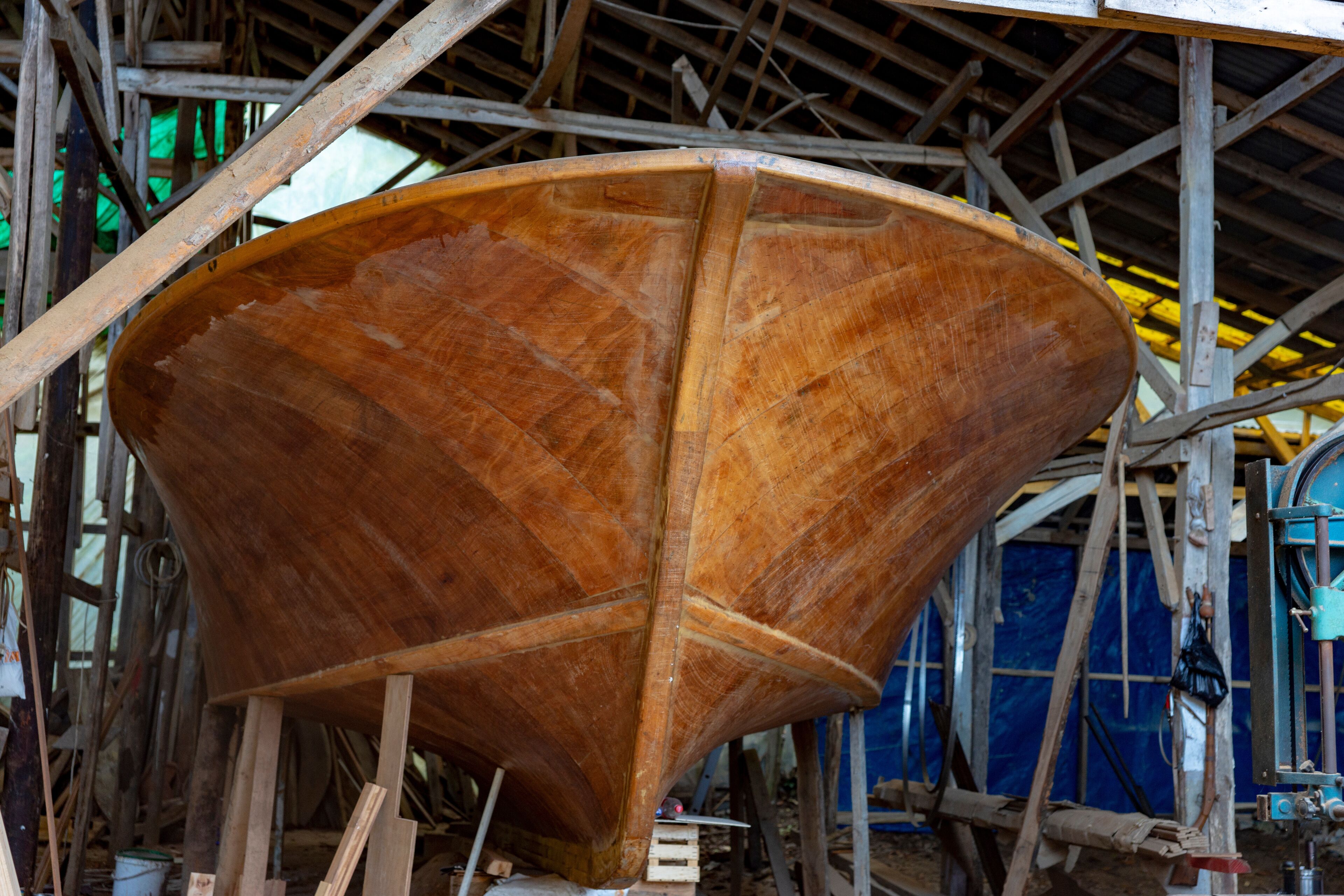 A large wooden boat under construction in a workshop with scaffolding.