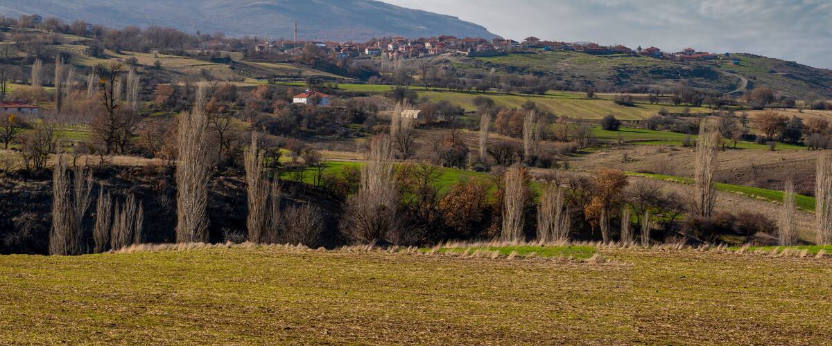 A rural landscape with rolling hills, scattered houses, and a prominent church spire.
