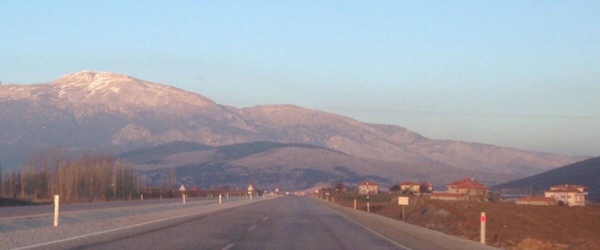 A road leading towards snow-capped mountains with a clear sky.