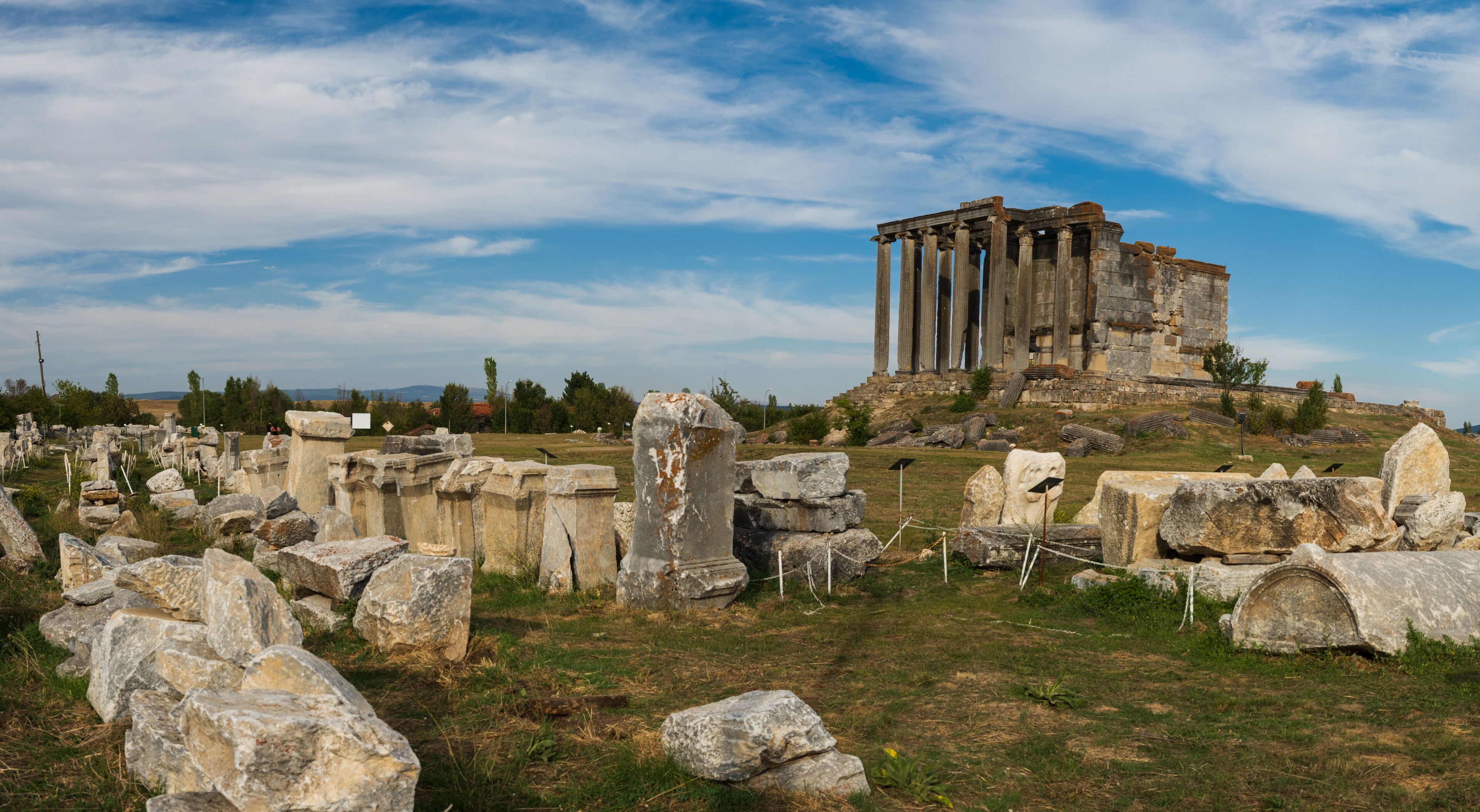 Ancient ruins with columns and scattered stones.