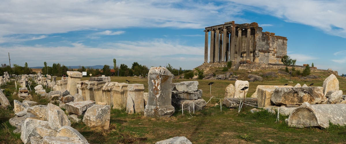 Ancient ruins with columns and scattered stones.