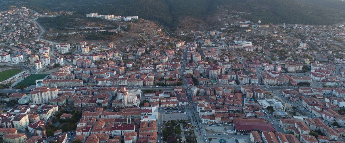A cityscape with dense residential buildings, a central square, and surrounding hills.