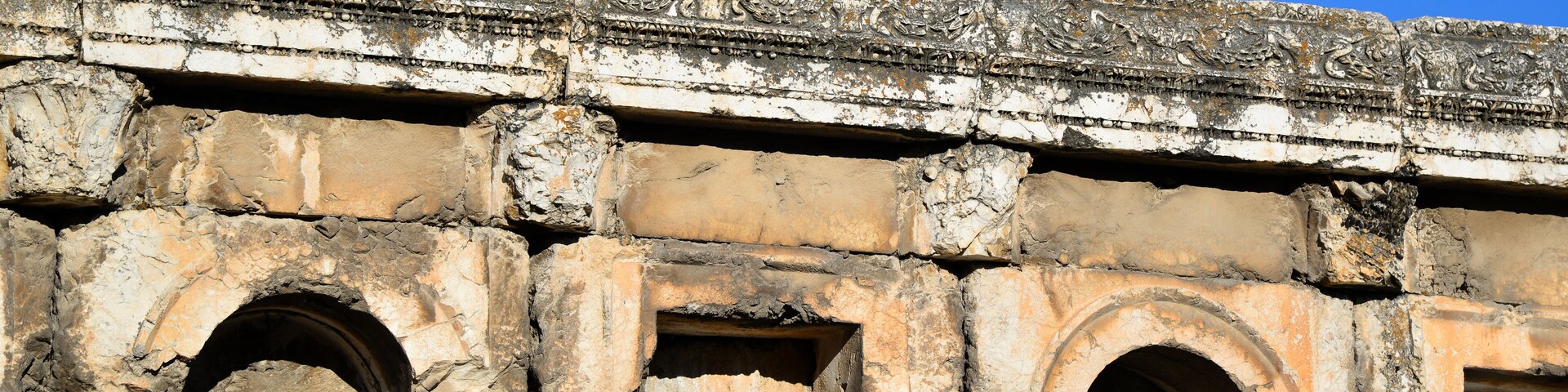 Arquitectura de piedra antigua con decoraciones talladas y arcos.