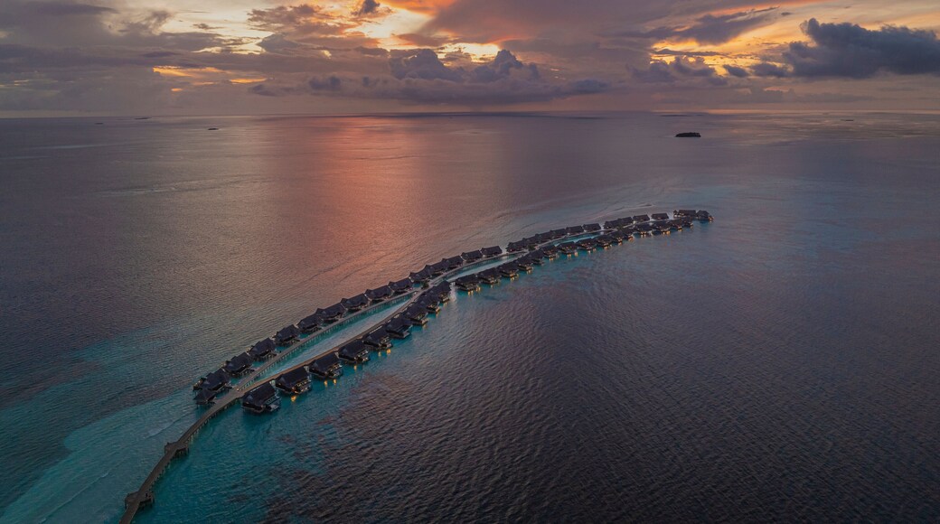 Aerial view of Muravandhoo Island at sunset with luxury resort and beautiful shoreline, Raa Atoll, Maldives.