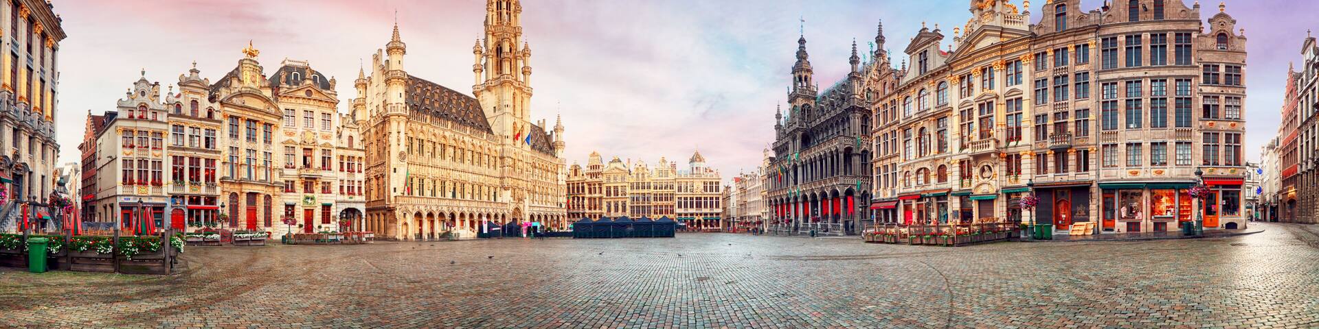 A historic European square with ornate buildings, a prominent tower, and cobblestone pavement.