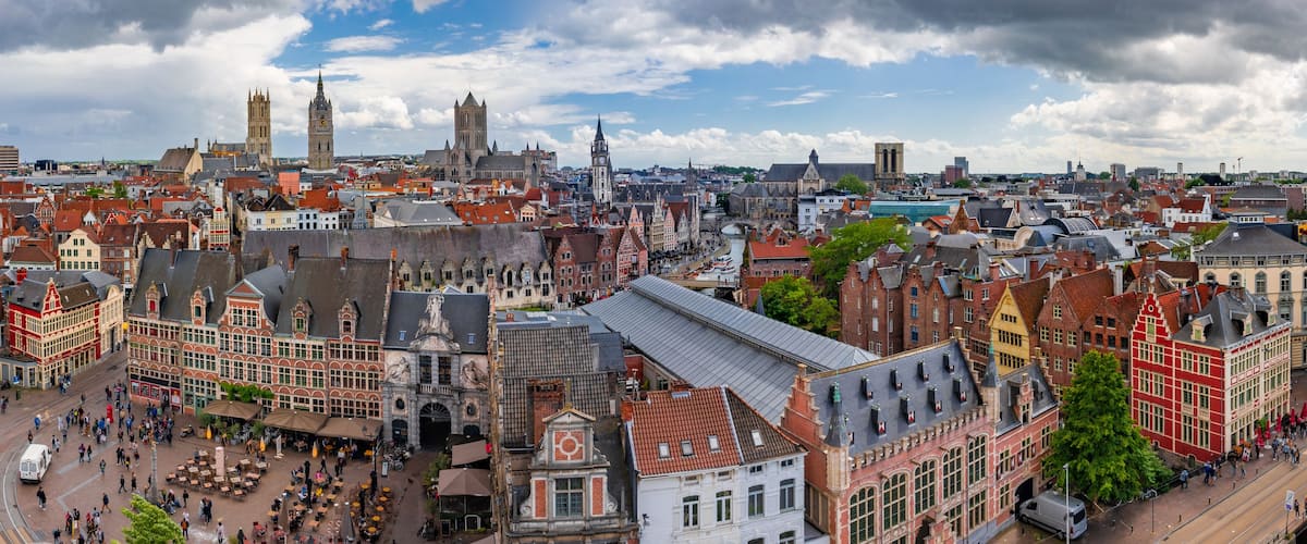 Un paysage urbain dense, avec des bâtiments historiques, une tour de l’horloge imposante et une rivière qui traverse le centre-ville.