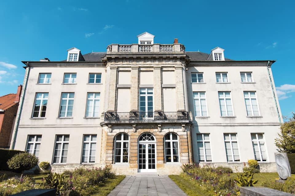Een groot, historisch gebouw met een symmetrische gevel, gebogen ramen en een centrale ingang.