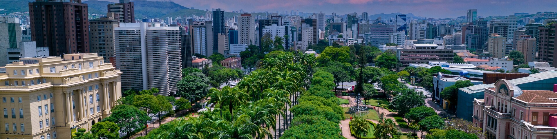 Paisagem urbana com um parque, com palmeiras e fontes.