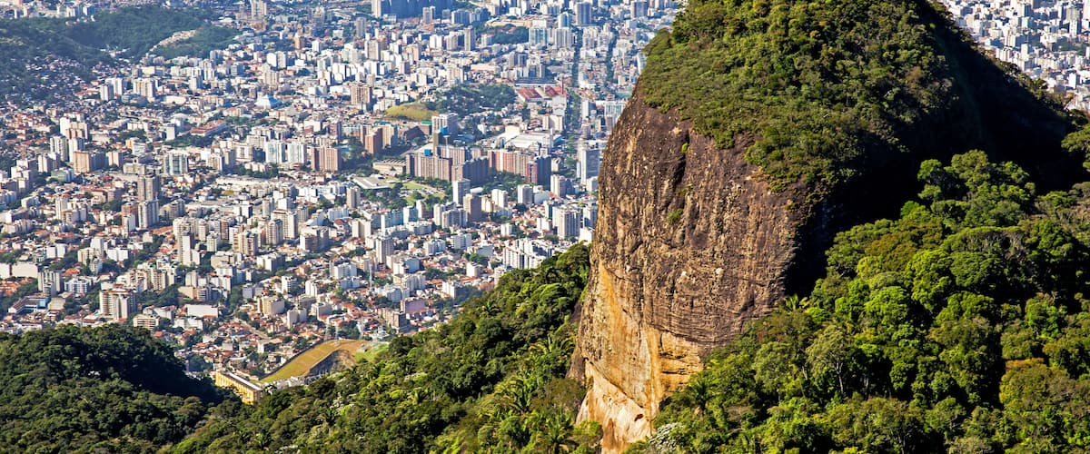 Un paisaje urbano con un pico montañoso destacado en primer plano y un puente al fondo.